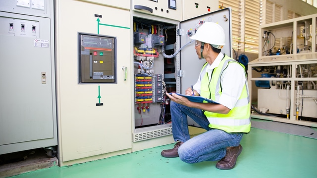 Técnico revisando cuadro eléctrico de baja tensión con protecciones y cableado en instalación industrial